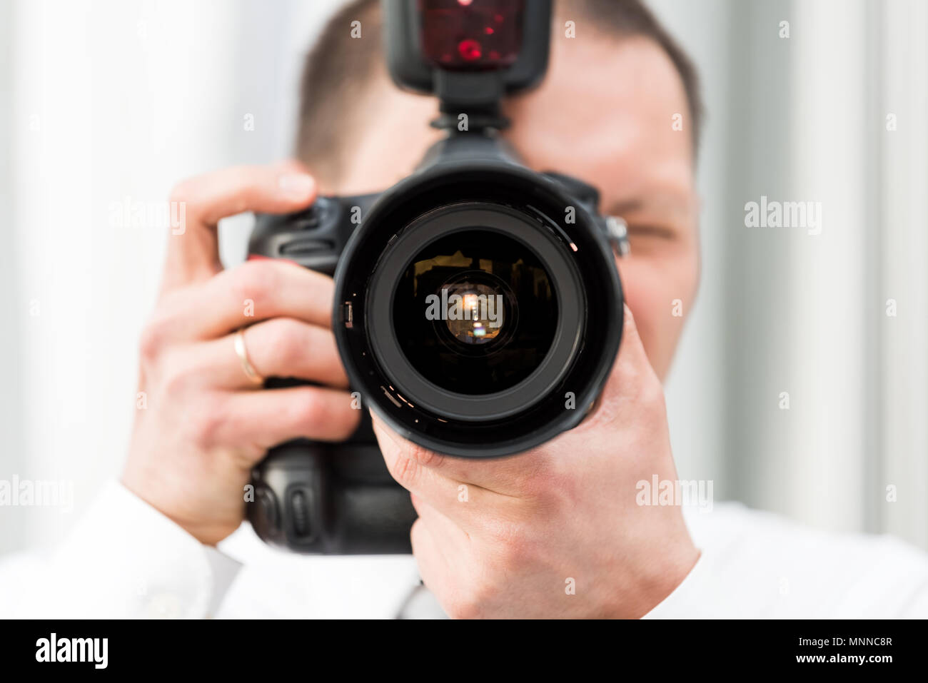 Un giovane fotografo per matrimoni, anello in Dress shirt in piedi con fotocamera flash esterni, scattare foto macro closeup della lente, riflessione Foto Stock