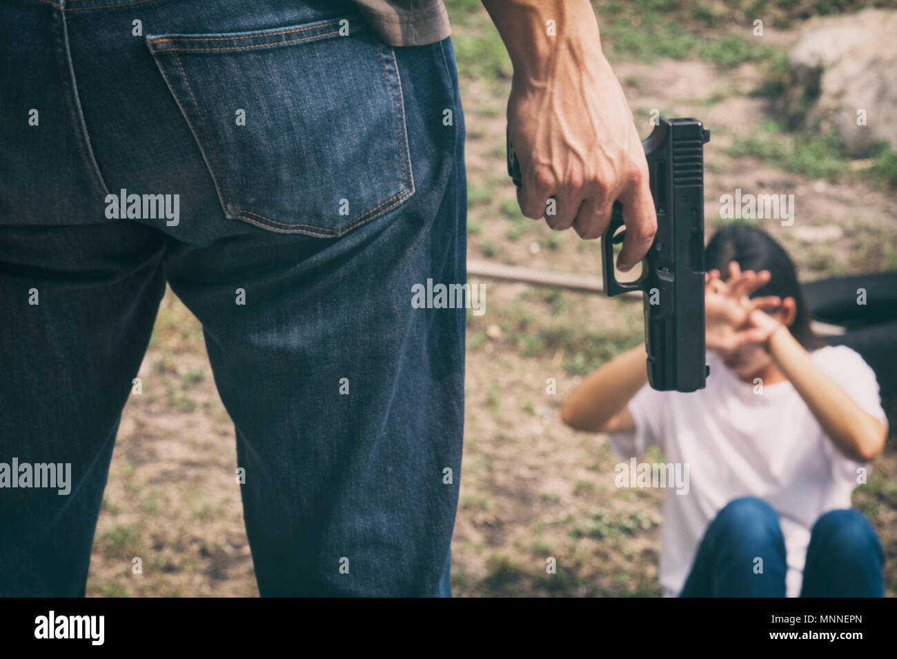 Bandit uomo pistola tenuta in piedi nella parte anteriore del giovane donna vittima sentimento di paura Foto Stock
