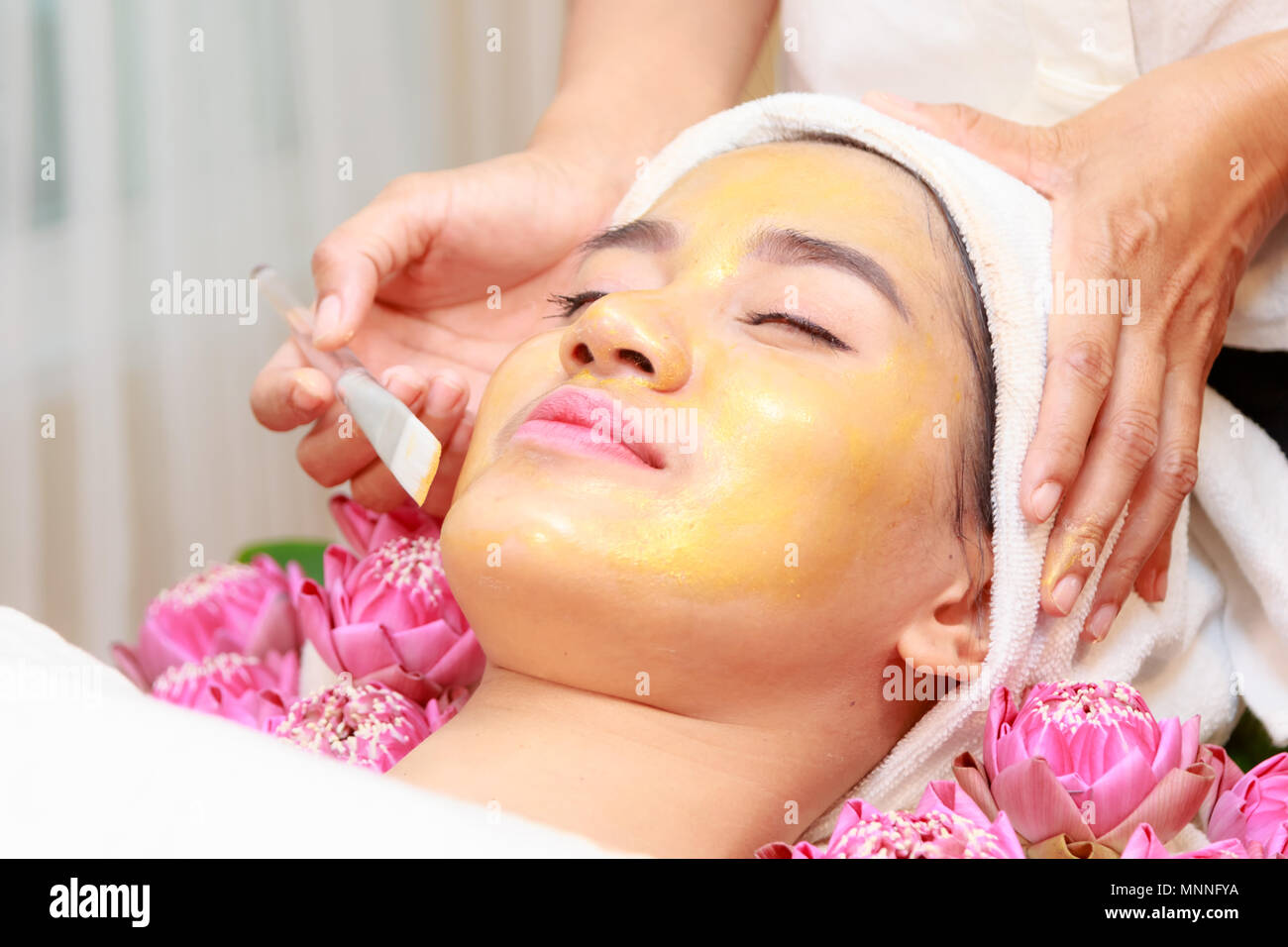 Felice relax donna getting oro maschera per il viso a un salone di bellezza. Foto Stock