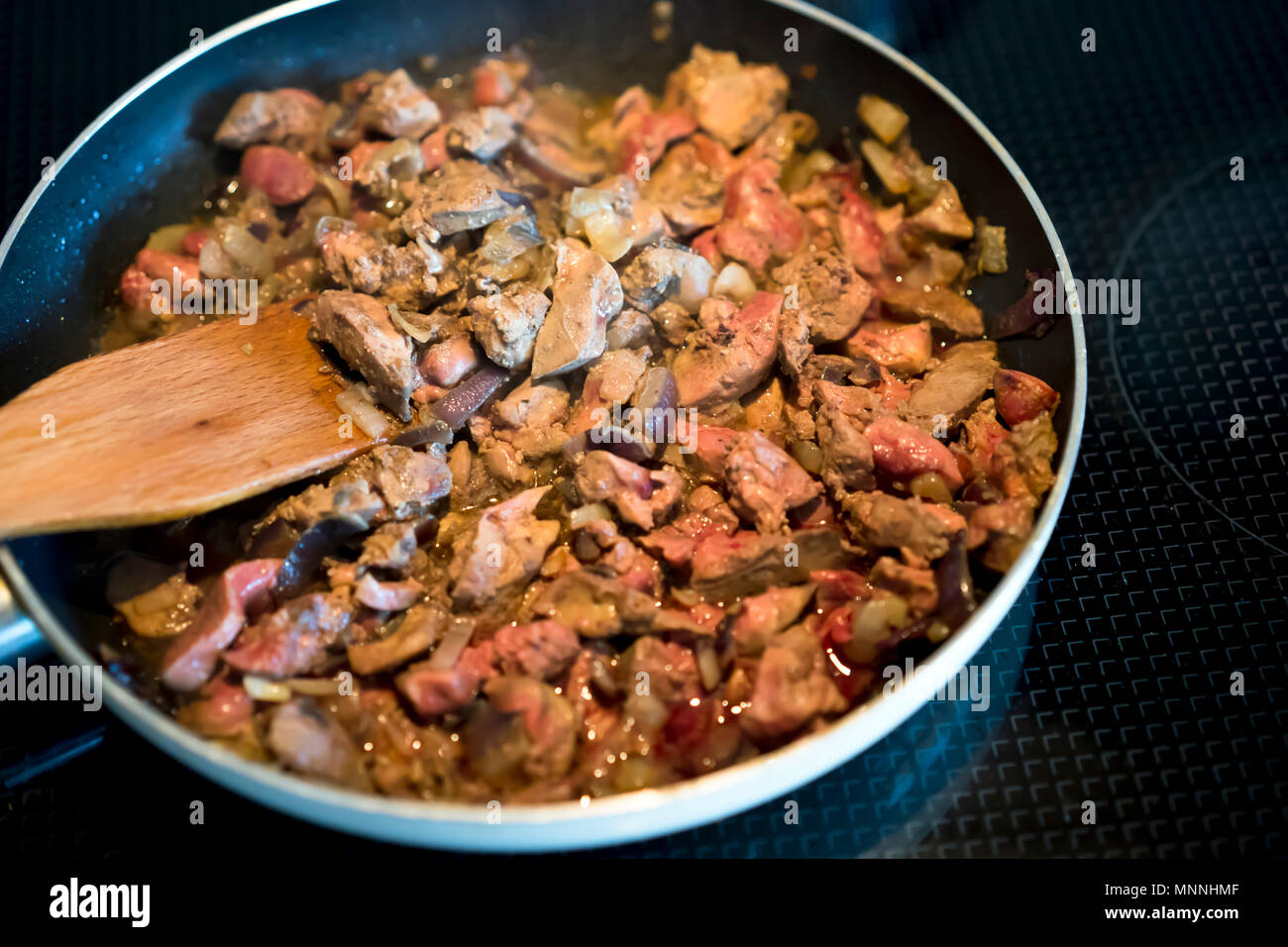Magnifica nutriente dietetico organico a fette di fegato di pollo con un elevato contenuto di proteine e ferro è attivamente fritte con cipolle in una padella finché non è Foto Stock