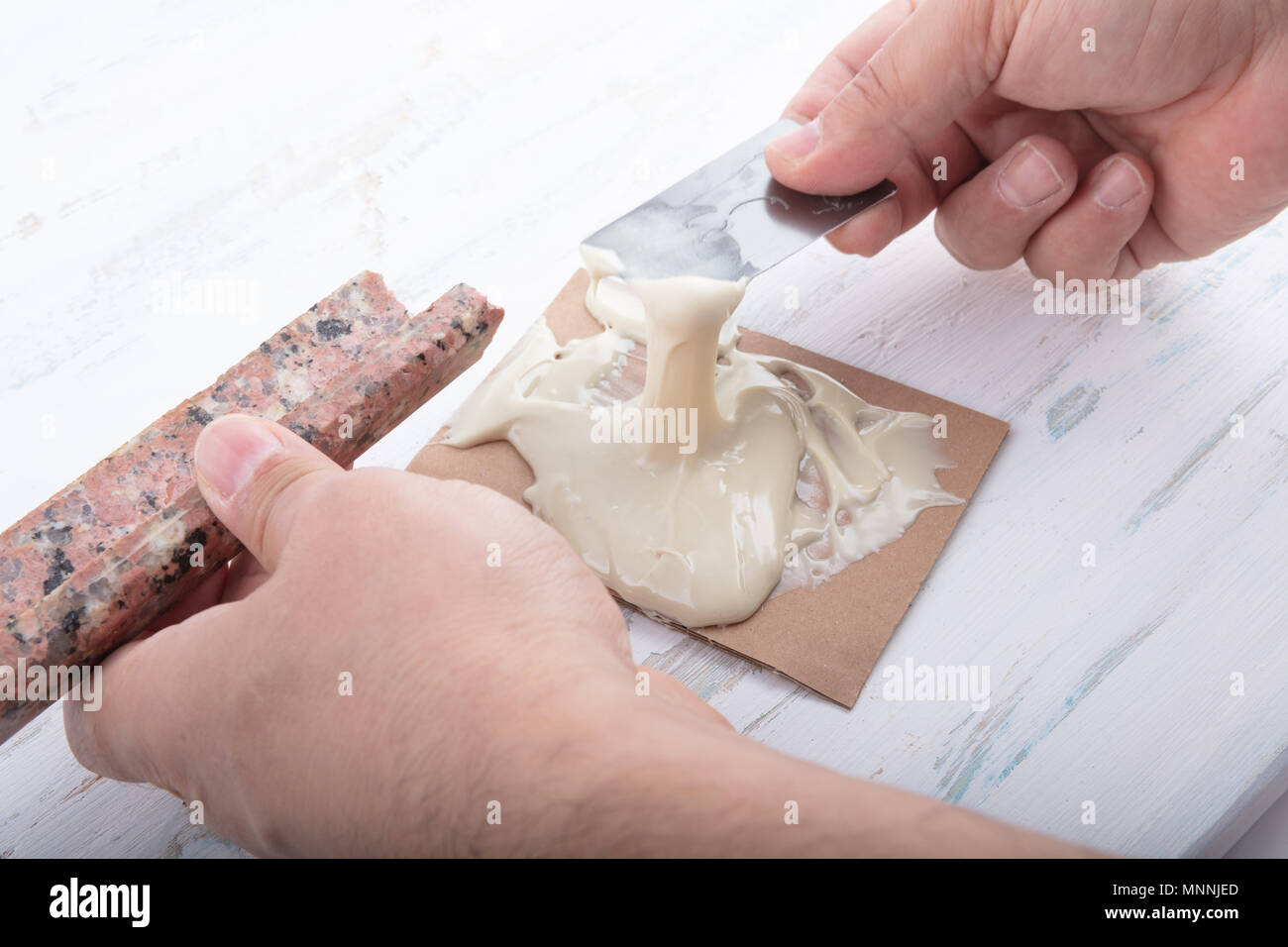 L'uomo la preparazione di adesivo bicomponente per la riparazione di marmo in una vista ravvicinata delle sue mani in un concetto di riparazioni DIY con spazio di copia Foto Stock