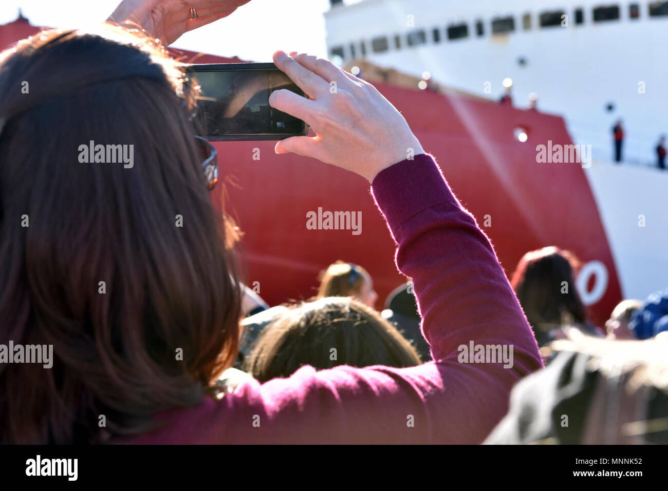 Un membro della famiglia prende una fotografia di un membro dell'equipaggio a bordo del guardacoste stella polare come l'equipaggio attracca al molo di base a Seattle, 16 marzo 2018. La Seattle-basato Stella Polare porta sinistra nel mese di dicembre per l'Antartide per supportare il funzionamento Deep Freeze 2018, il militare degli Stati Uniti a dare il suo contributo di US Programma antartico, che è gestito dalla Fondazione di Scienza Nazionale. Stati Uniti Coast Guard Foto Stock