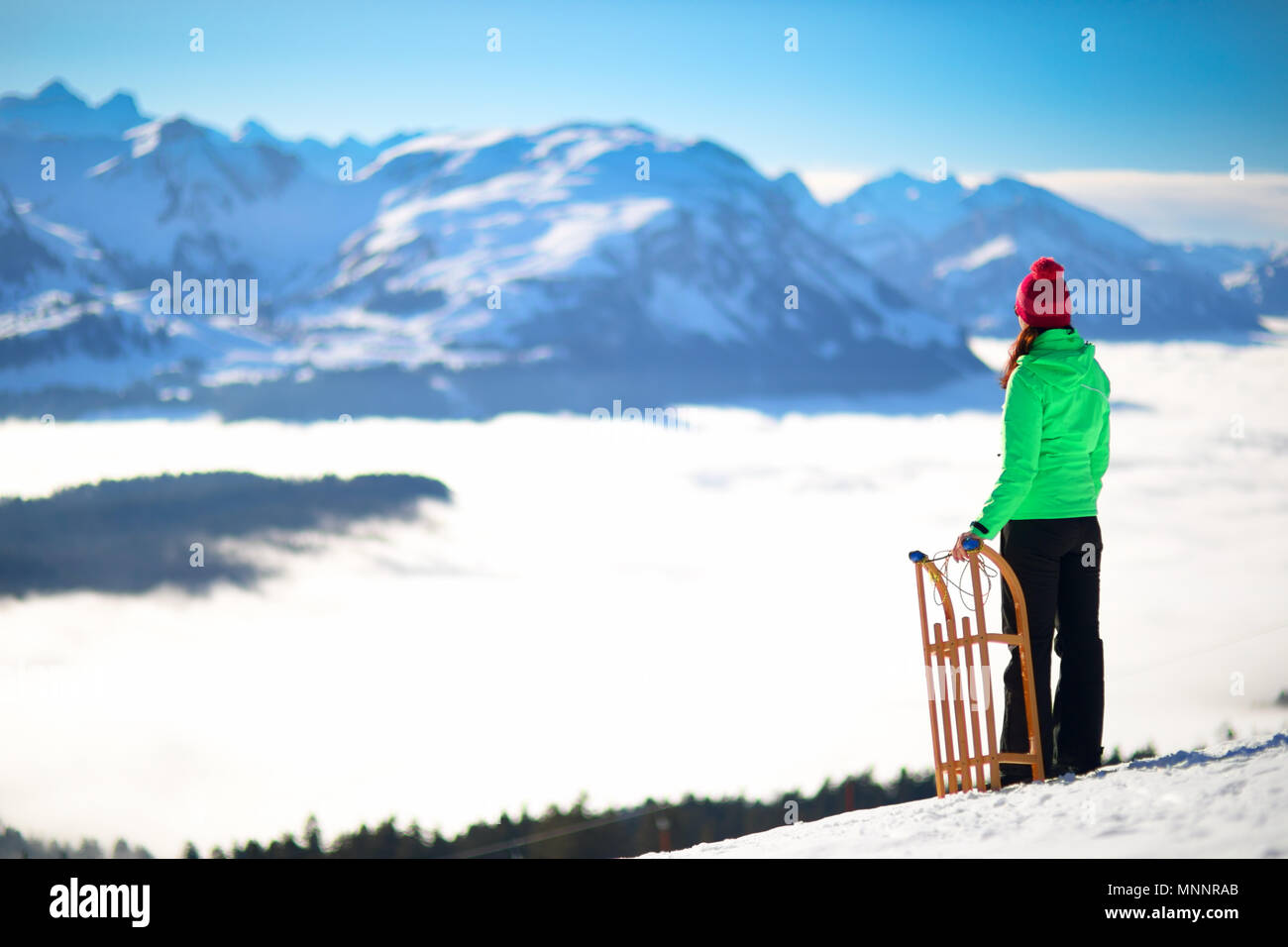 Giovane donna attraente pronto per andare in slittino nelle Alpi durante la vacanza invernale. Foto Stock