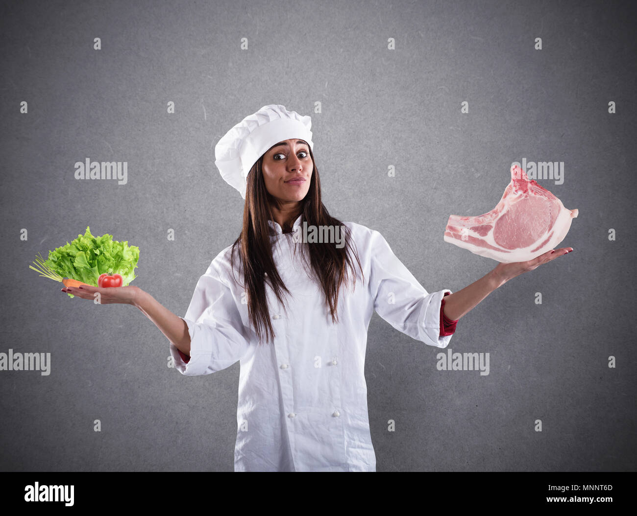 Lo Chef indecisi tra insalata fresca o bistecca di carne. concetto di vegetariano Foto Stock