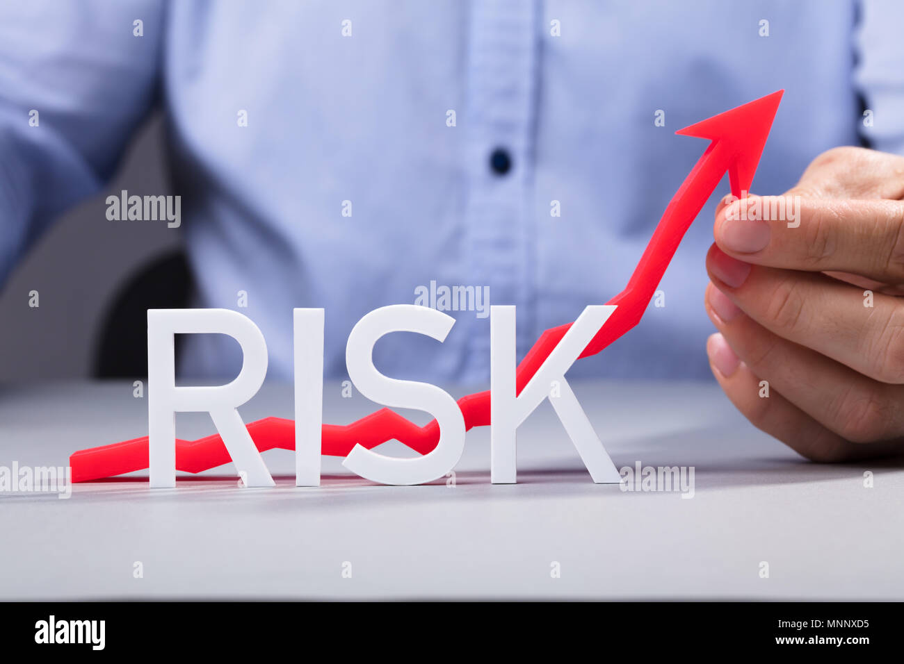 I mediatori azienda rosso freccia crescente dietro la parola del rischio del testo in tabella Foto Stock