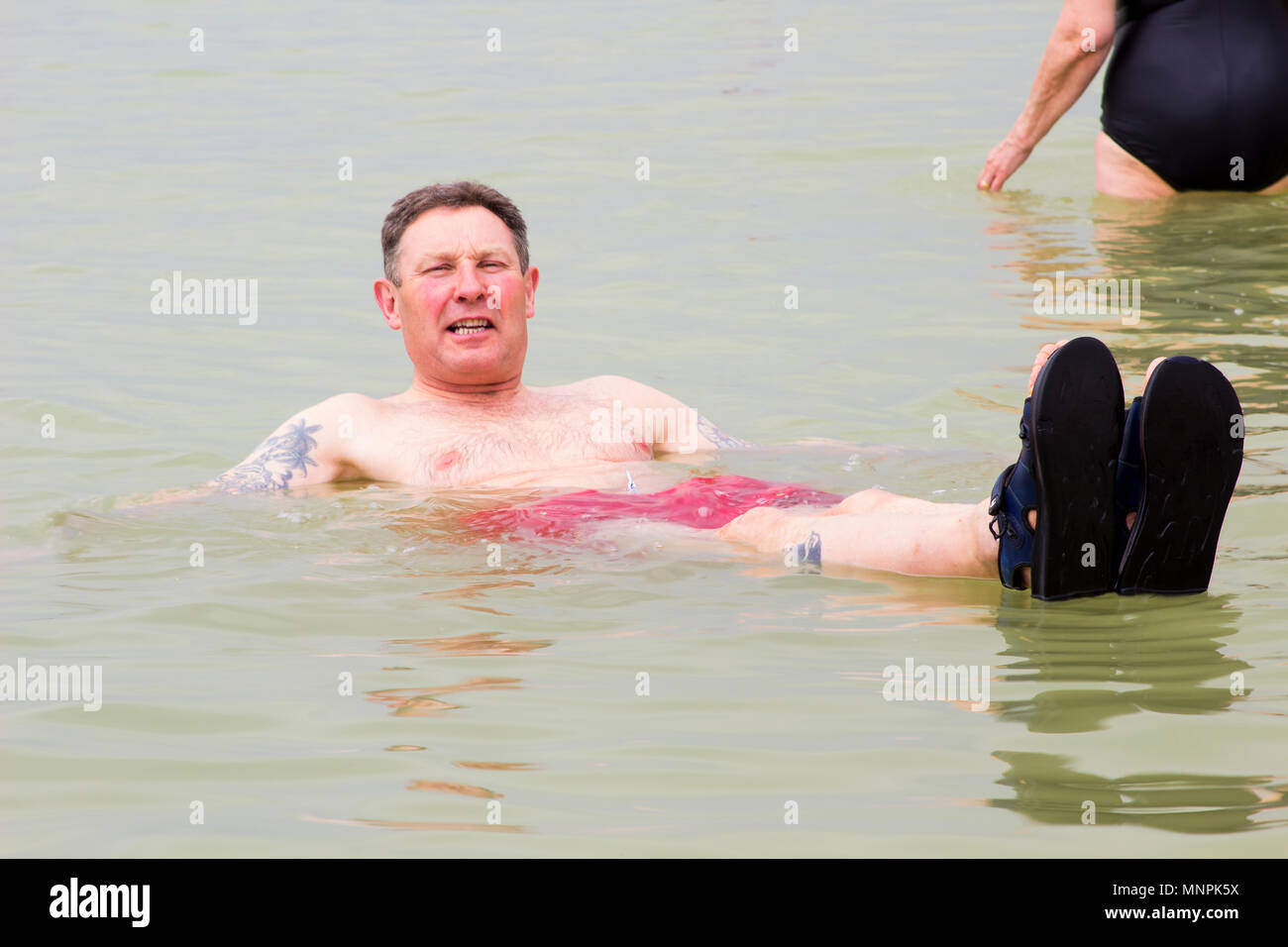 8 maggio 2018 un turista galleggia nell'acqua salata del Mar Morto alla spiaggia di molti hotel in Ein Bokek area d'Israele Foto Stock