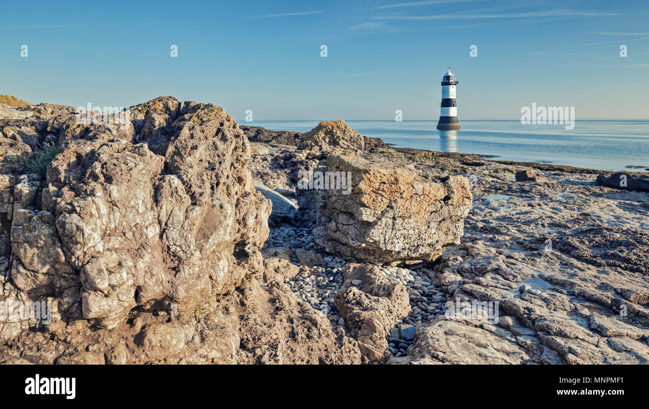 Vista Panormaic di Penmon Point lighthouse ed eroso shore cliff a bright mattina di sole. Isola di Anglesey nel Galles del Nord, Regno Unito Foto Stock