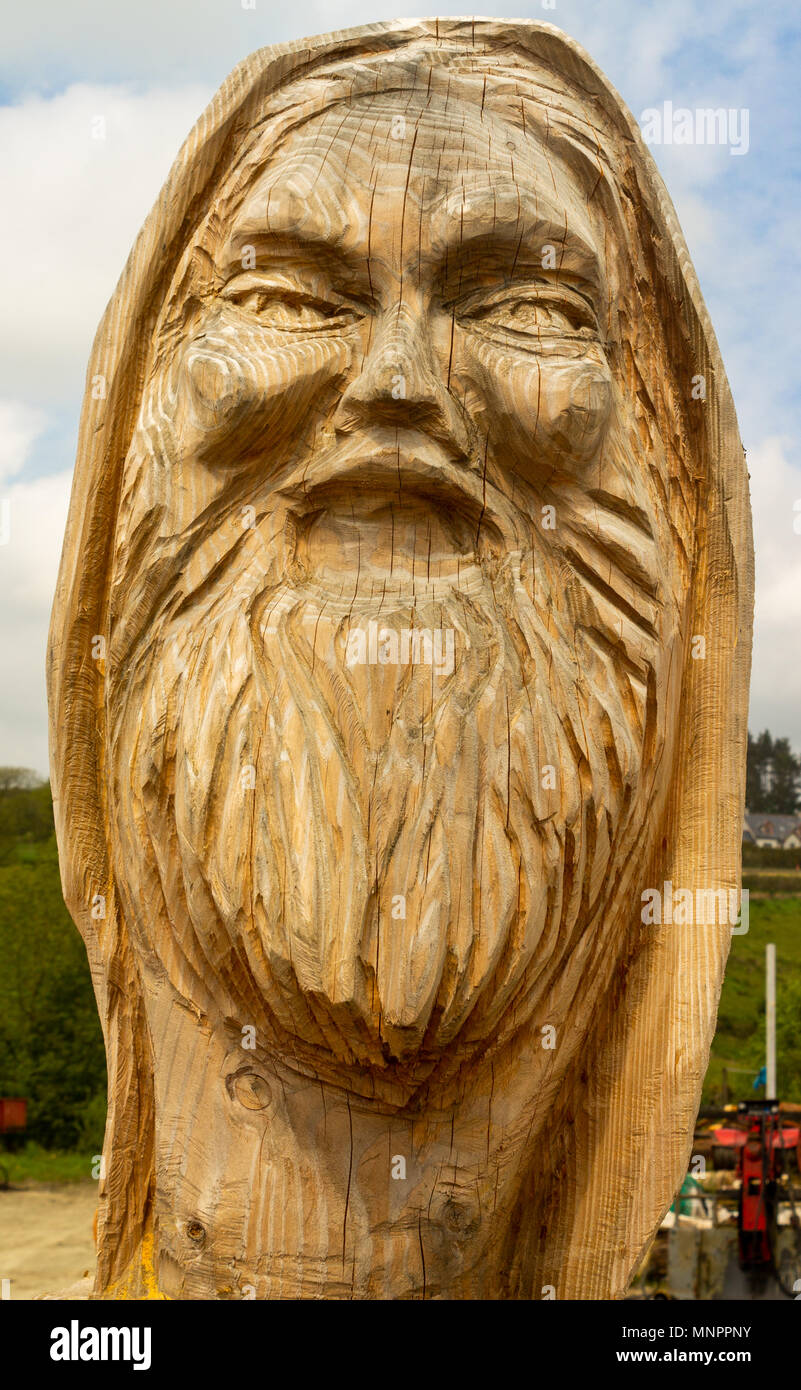 Intaglio del legno di un barbuto mans testa tagliata da un solido pezzo di tronco di albero in un intagliatori del legno in cantiere drimoleague, Irlanda. Foto Stock