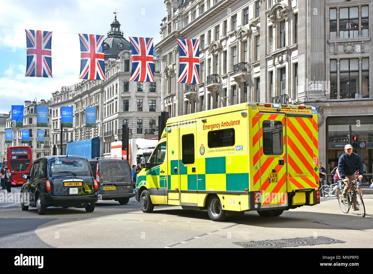 London street scene NHS ambulanza di emergenza in Oxford Circus ingorghi di traffico attesa di accedere a Regent Street ciclista bike allo svincolo West End union jack UK Foto Stock