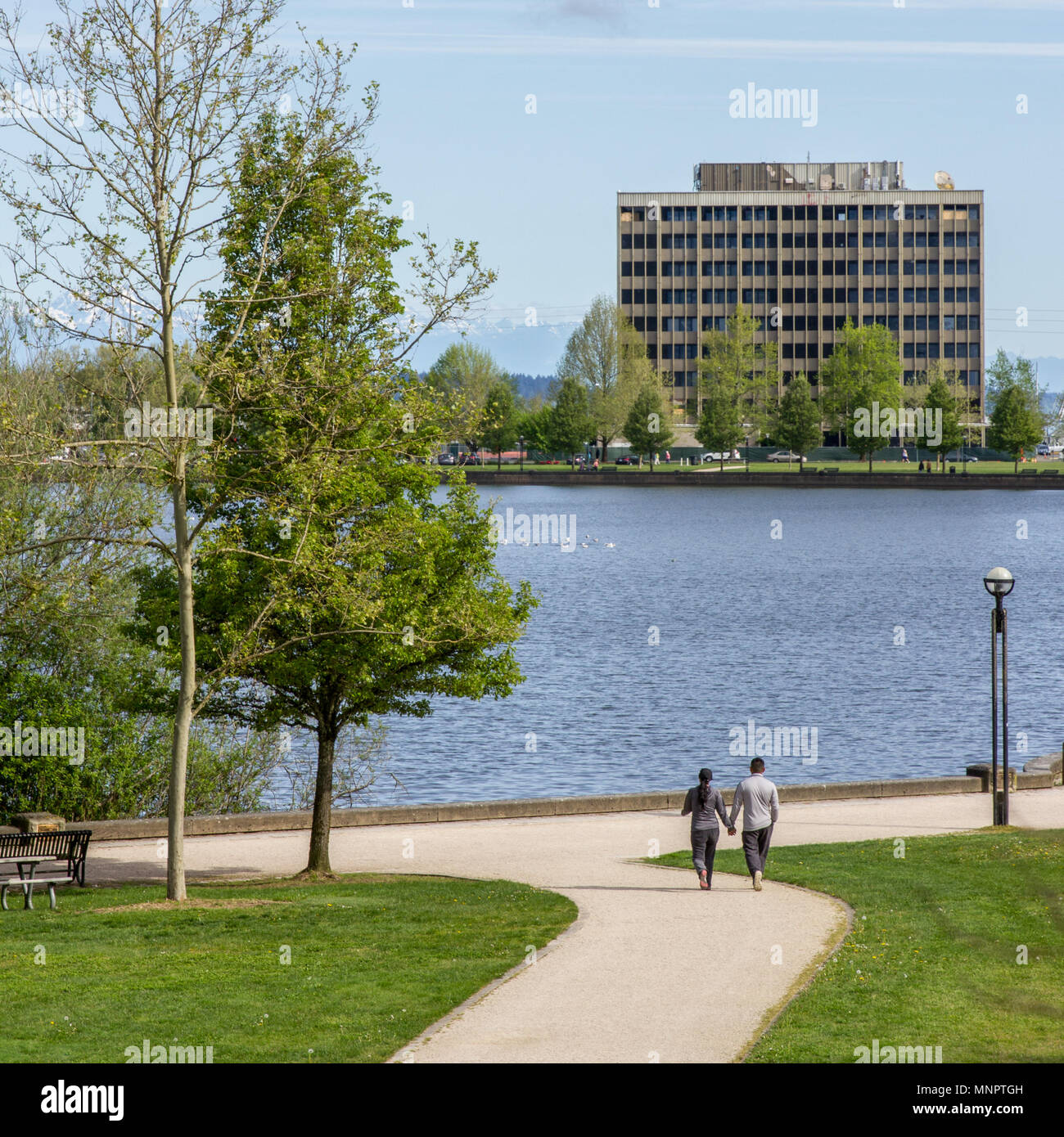 Olympia, Washington / STATI UNITI D'America - 5 Maggio 2018: persone passeggiare e correre attraverso il Capitol Lake Park con le Montagne Olimpiche visibile in distanza. Foto Stock