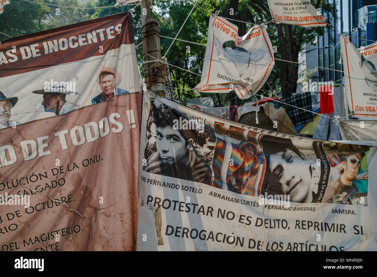 Facce di 2014 Iguala studenti mancanti sul banner vengono visualizzati dagli attivisti che sono state camping sul Paseo de Reforma, Città del Messico. Foto Stock