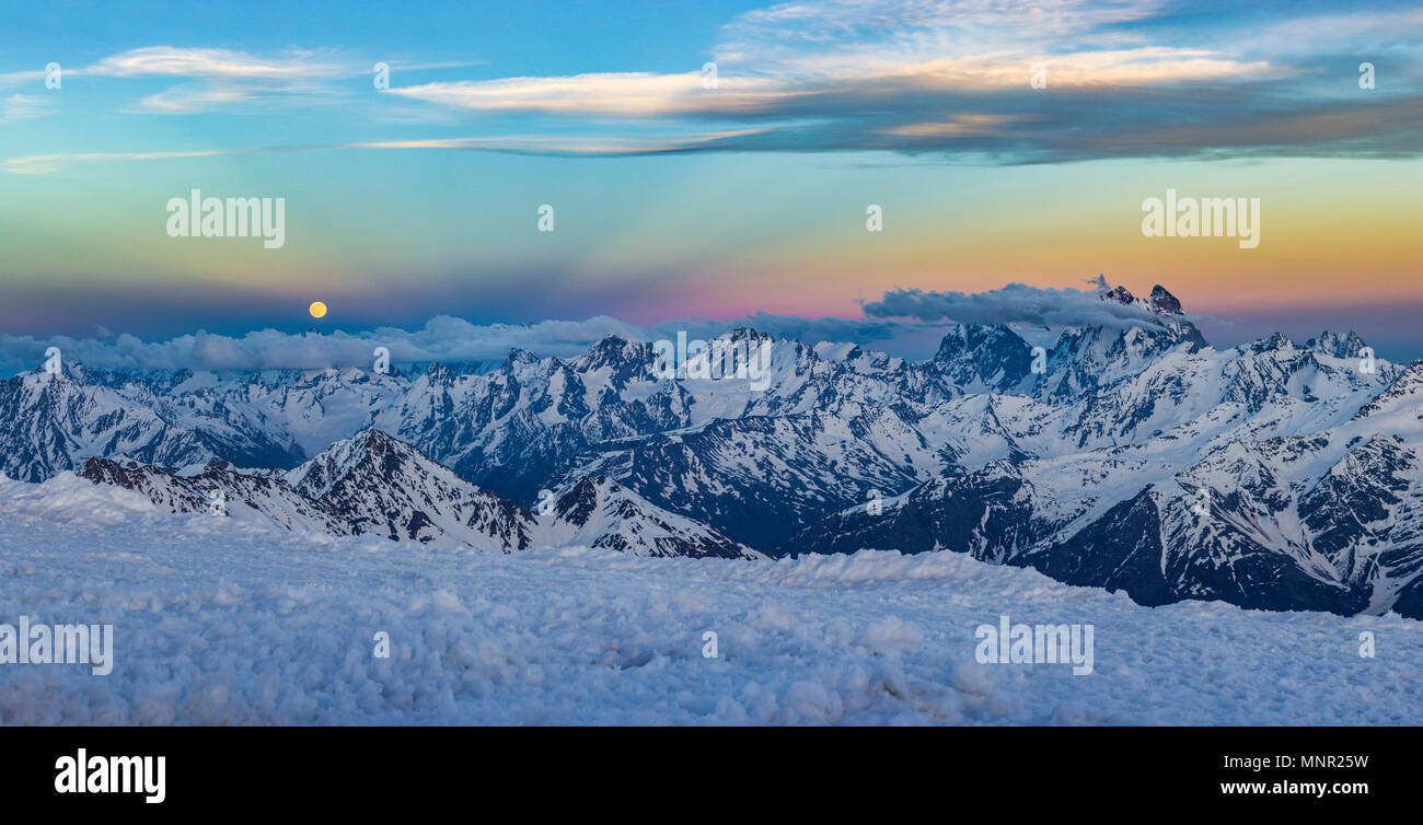 Caucaso innevate montagne con ghiacciai al tramonto da elbrus pendii con pietre e nuvole sul cielo blu Foto Stock
