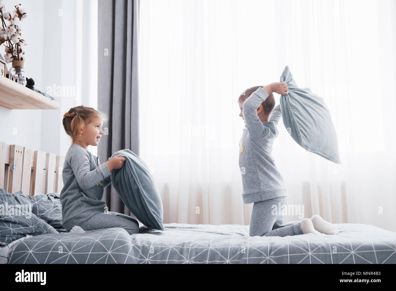 Piccolo Ragazzo e ragazza in scena una lotta di cuscini sul letto in camera  da letto. Bambini cattivi battere ogni altri cuscini. A loro piace quel  tipo di gioco Foto stock -