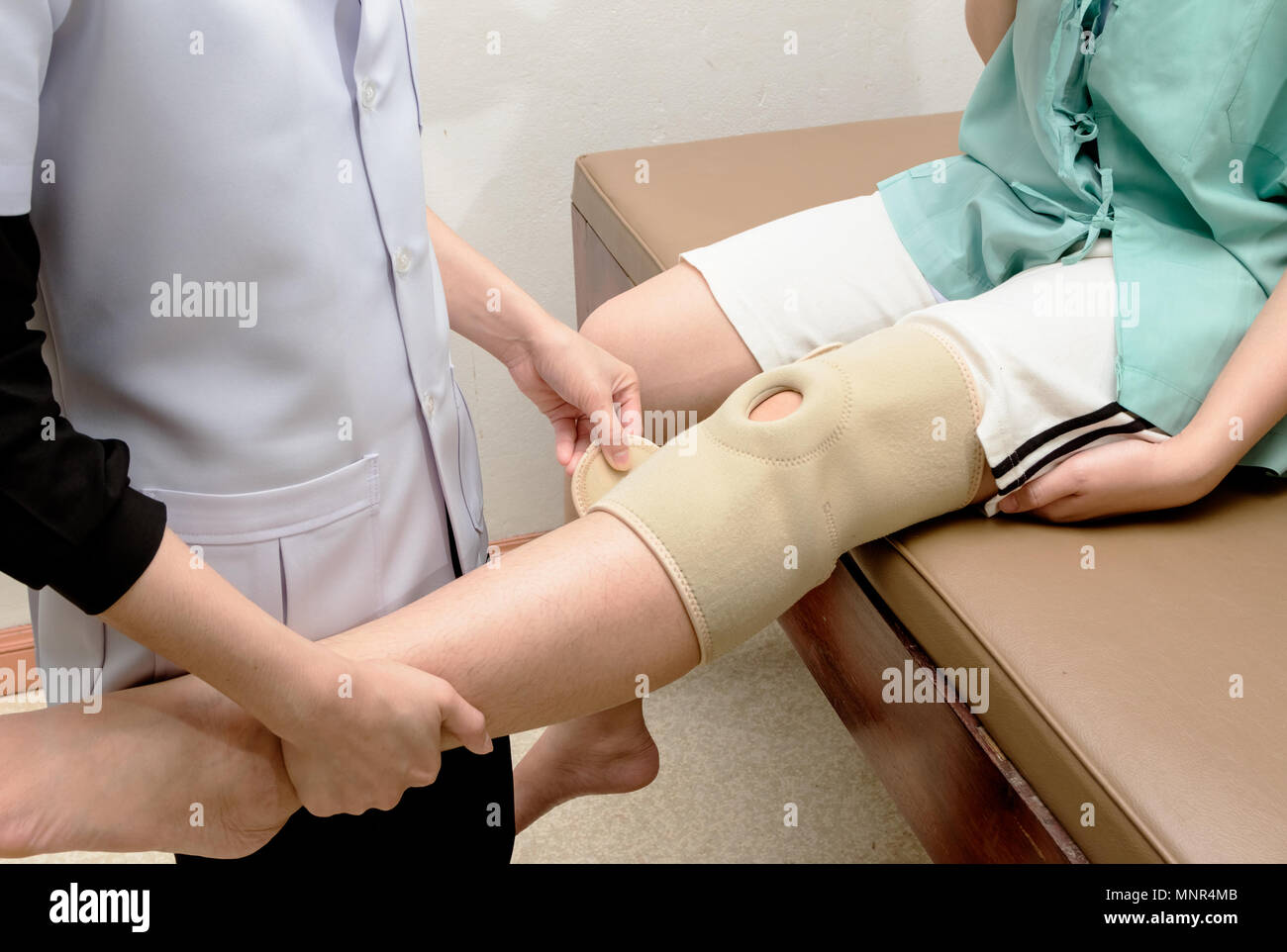 Fisioterapista applicazione Supporto ginocchio al ginocchio del paziente,la riabilitazione Foto Stock