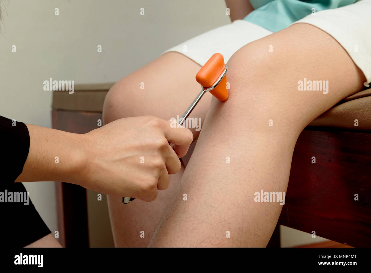 Medico di fare l'esame del ginocchio prova di riflesso sul ginocchio del paziente,test di neurologia Foto Stock