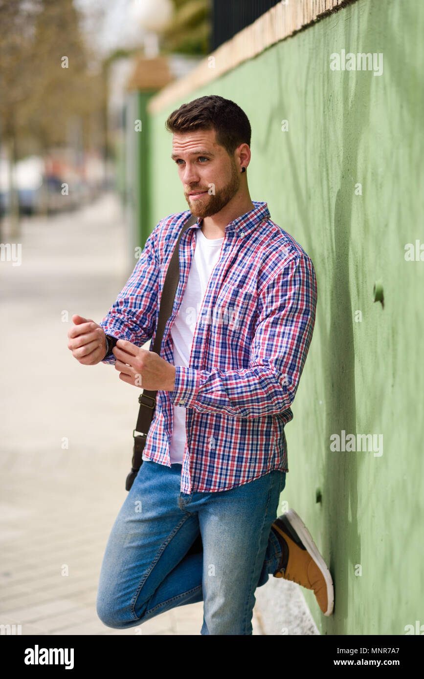 Attraente giovane uomo in piedi in background urbano. Ragazzo indossa abiti casual. Il concetto di stile di vita. Foto Stock