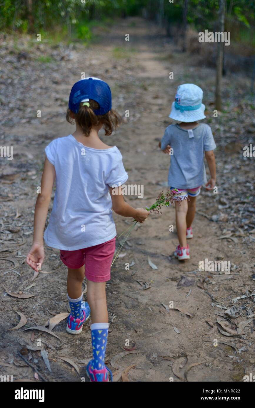 Due giovani ragazza camminare su una pista sterrata attraverso una foresta, Rollingstone QLD, Australia Foto Stock