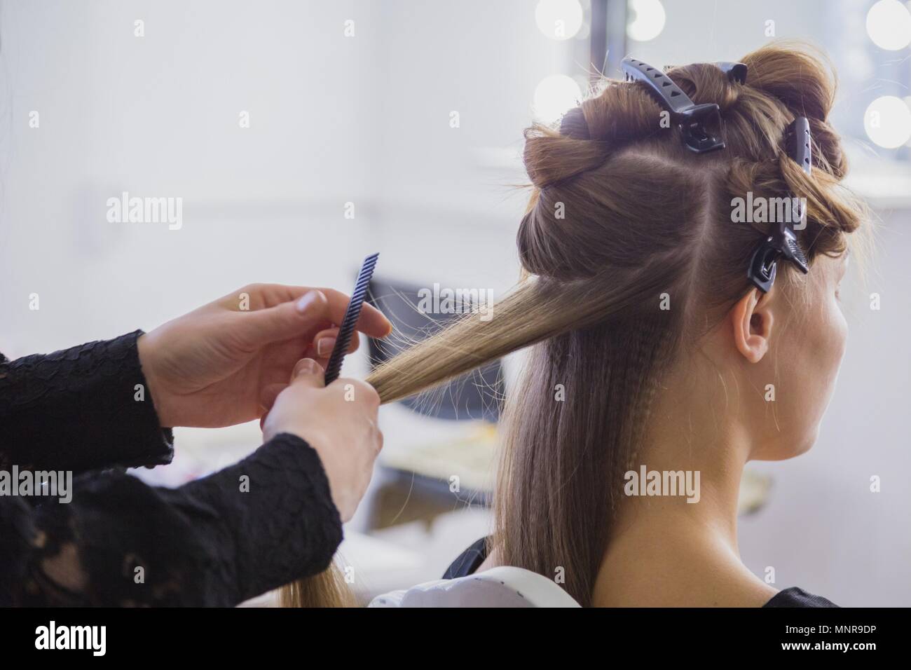 Parrucchiere professionale fare l'acconciatura per giovane bella donna con capelli lunghi Foto Stock