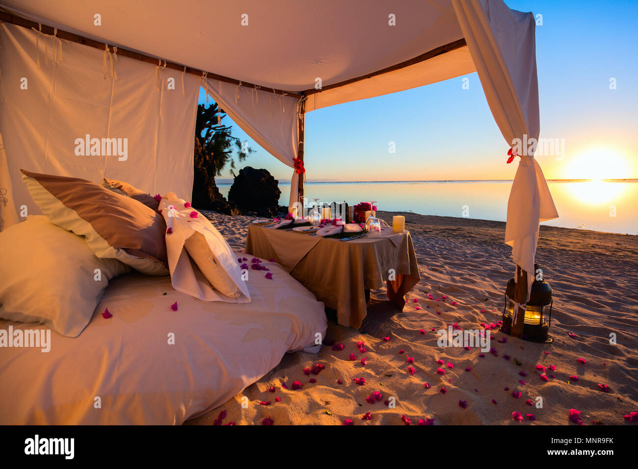 Romantica cena di lusso impostazione alla spiaggia tropicale sul tramonto Foto Stock