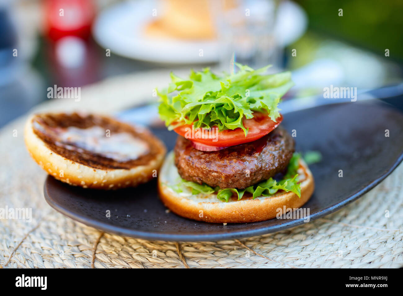 Close up assemblaggio di freschi e deliziosi burger con pomodoro e una fresca insalata verde Foto Stock