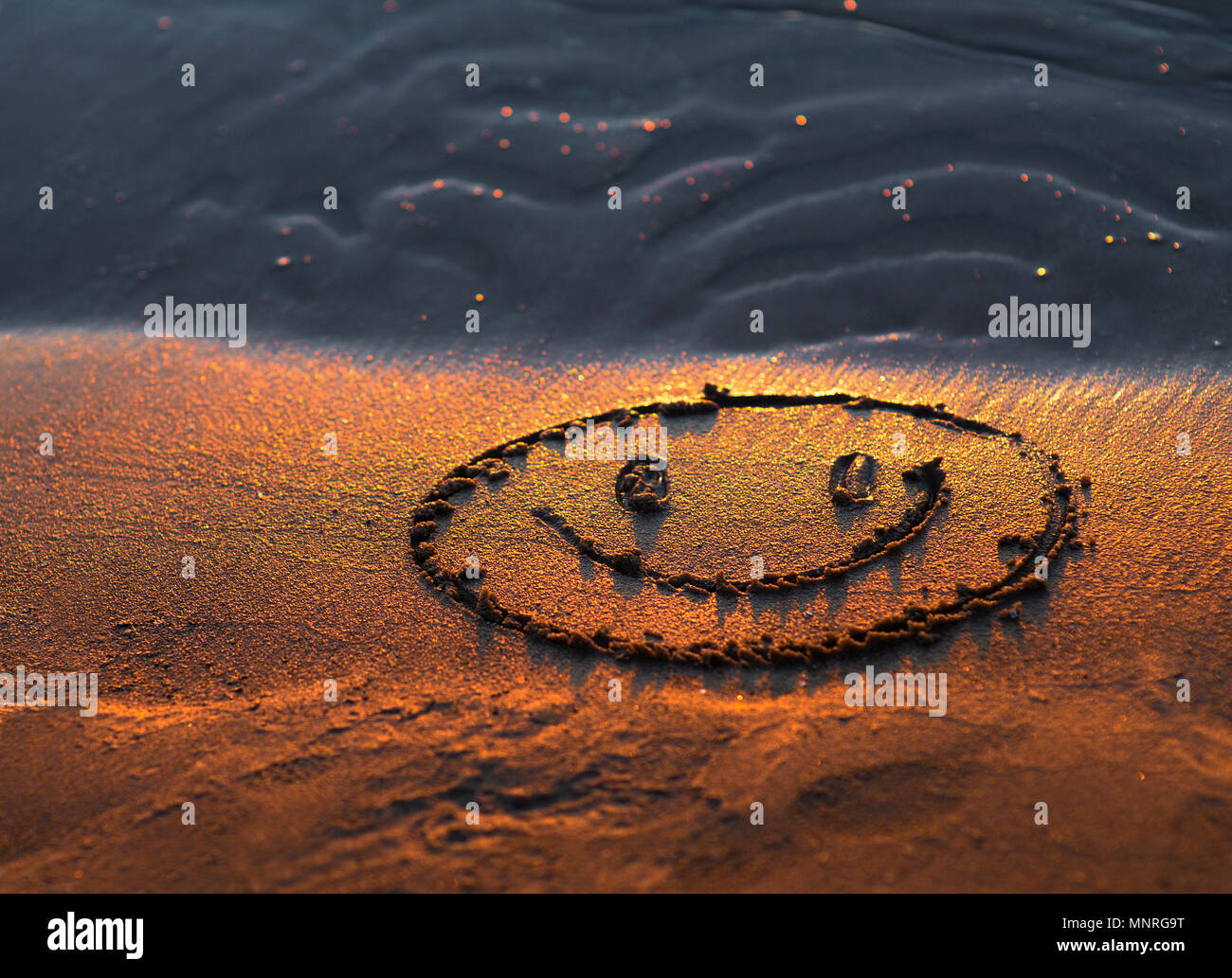 Felice volto sorridente nella sabbia. Gli occhi e la bocca disegnata con un dito asciutto ocherous sabbia. Foto macro close up dal di sopra. Foto Stock