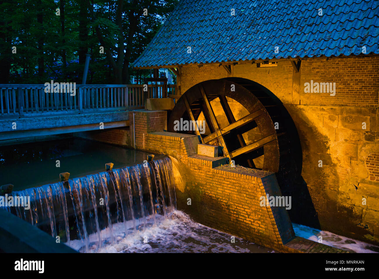 Piccolo fiume storico con ruota a pale in Haarmuhle, in Germania, in Europa, questo è ancora funzionante e più di 400 anni di sera con luci Foto Stock