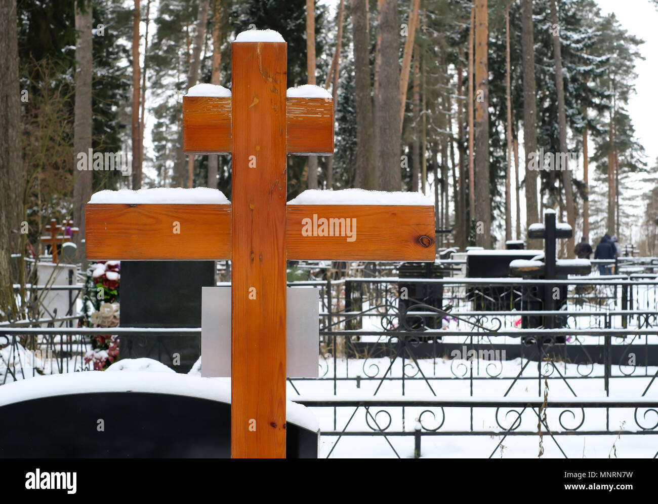 Croce di legno e fiori artificiali sulla tomba di un cimitero di ortodossi in inverno Foto Stock