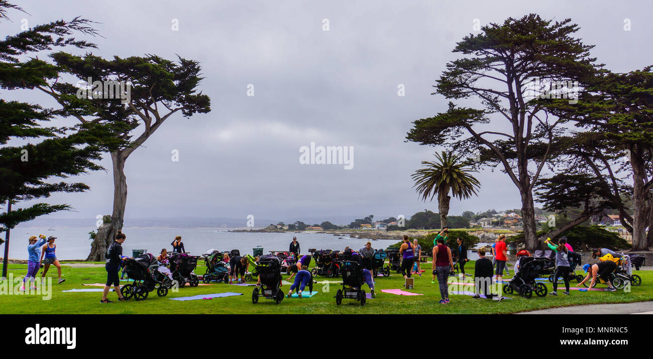 Le madri con i neonati e i bambini piccoli nei passeggini fare esercizio di classe in parte con un bellissimo mare costa impostazione a Monterey in California Foto Stock