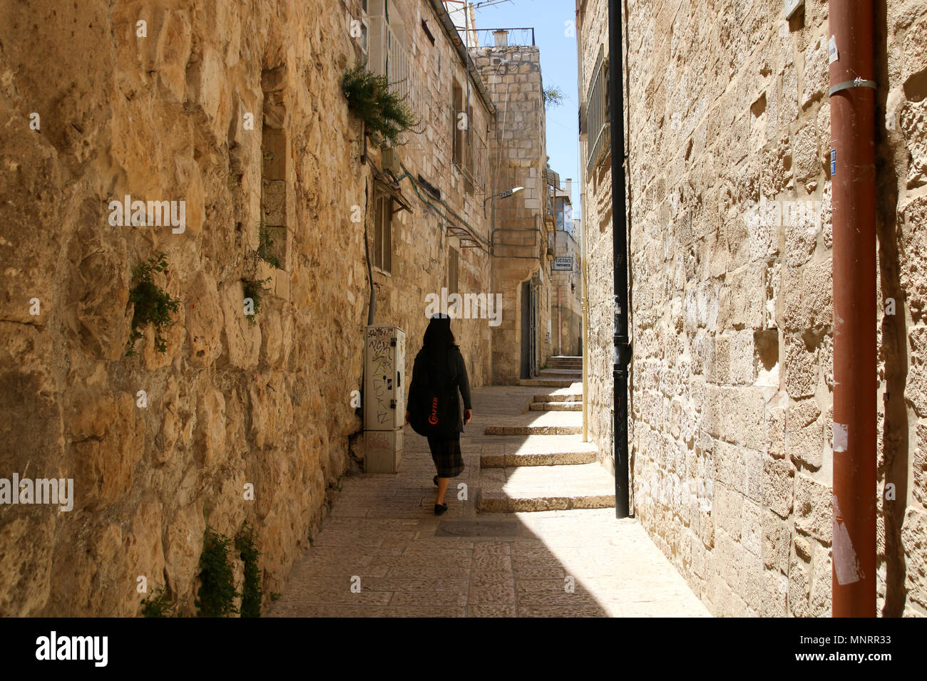 Gerusalemme, Israele - 16 Maggio 2018: una donna vestita di nero passeggiate nel sole di mezzogiorno attraverso la città vecchia di Gerusalemme, Tel Aviv. Foto Stock
