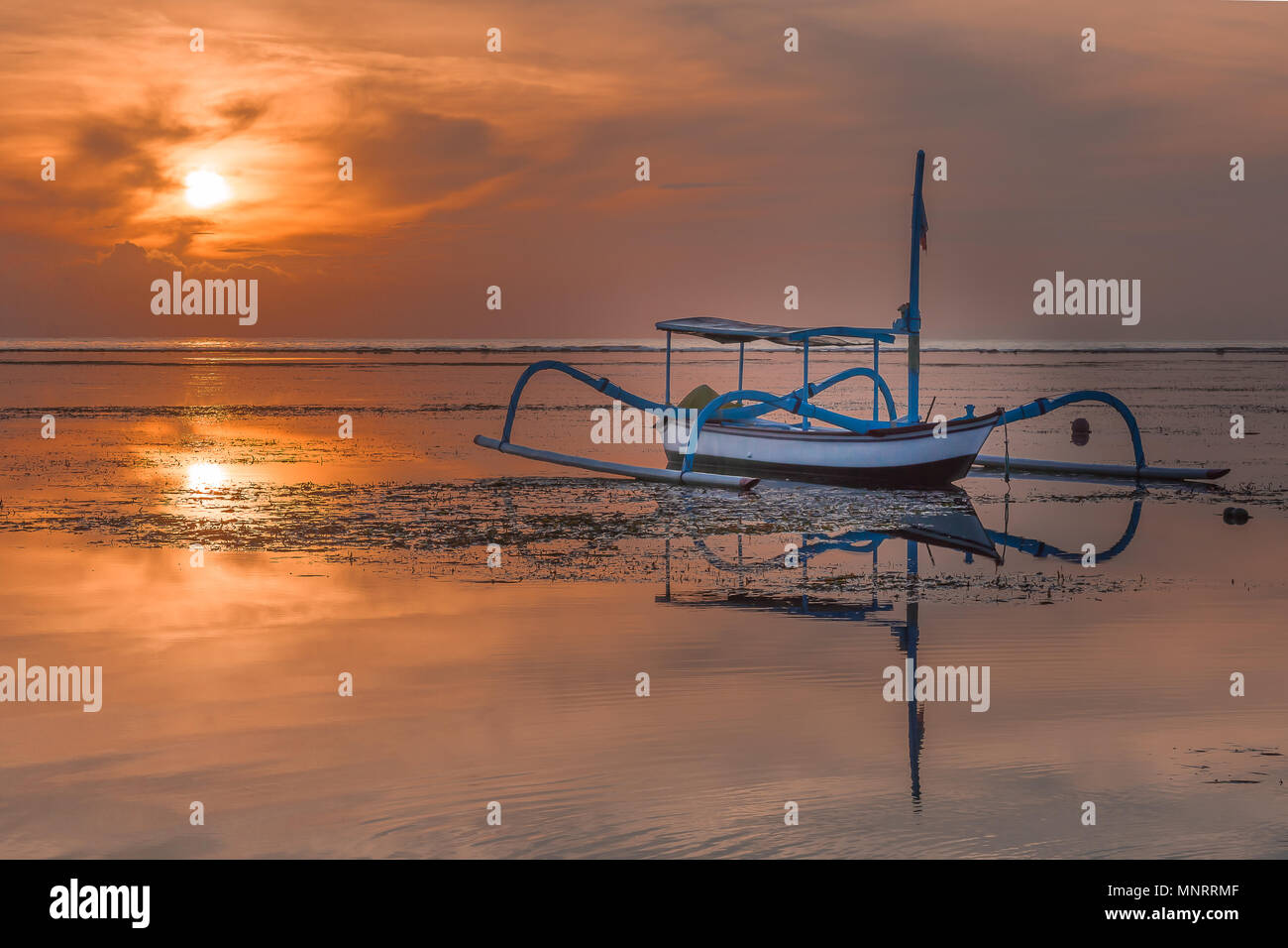 Un indonesiano barca da pesca di sunrise, riflessi nell'acqua, Sanur, Bali, Indonesia, 21 aprile 2018 Foto Stock