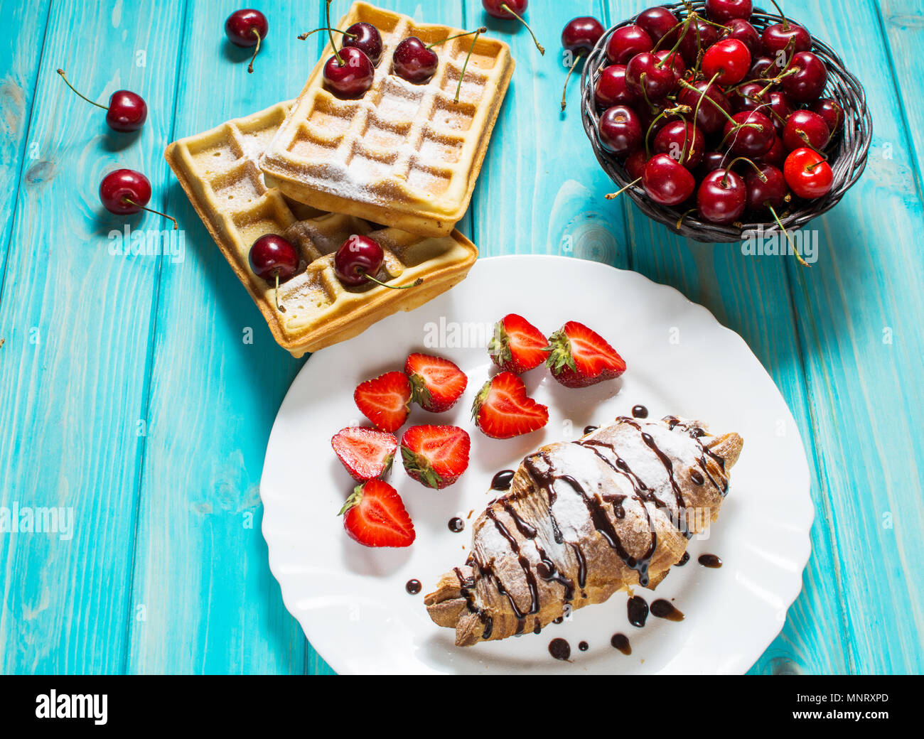 La prima colazione : cialde e croissant con ciliegie e fragole. Foto Stock