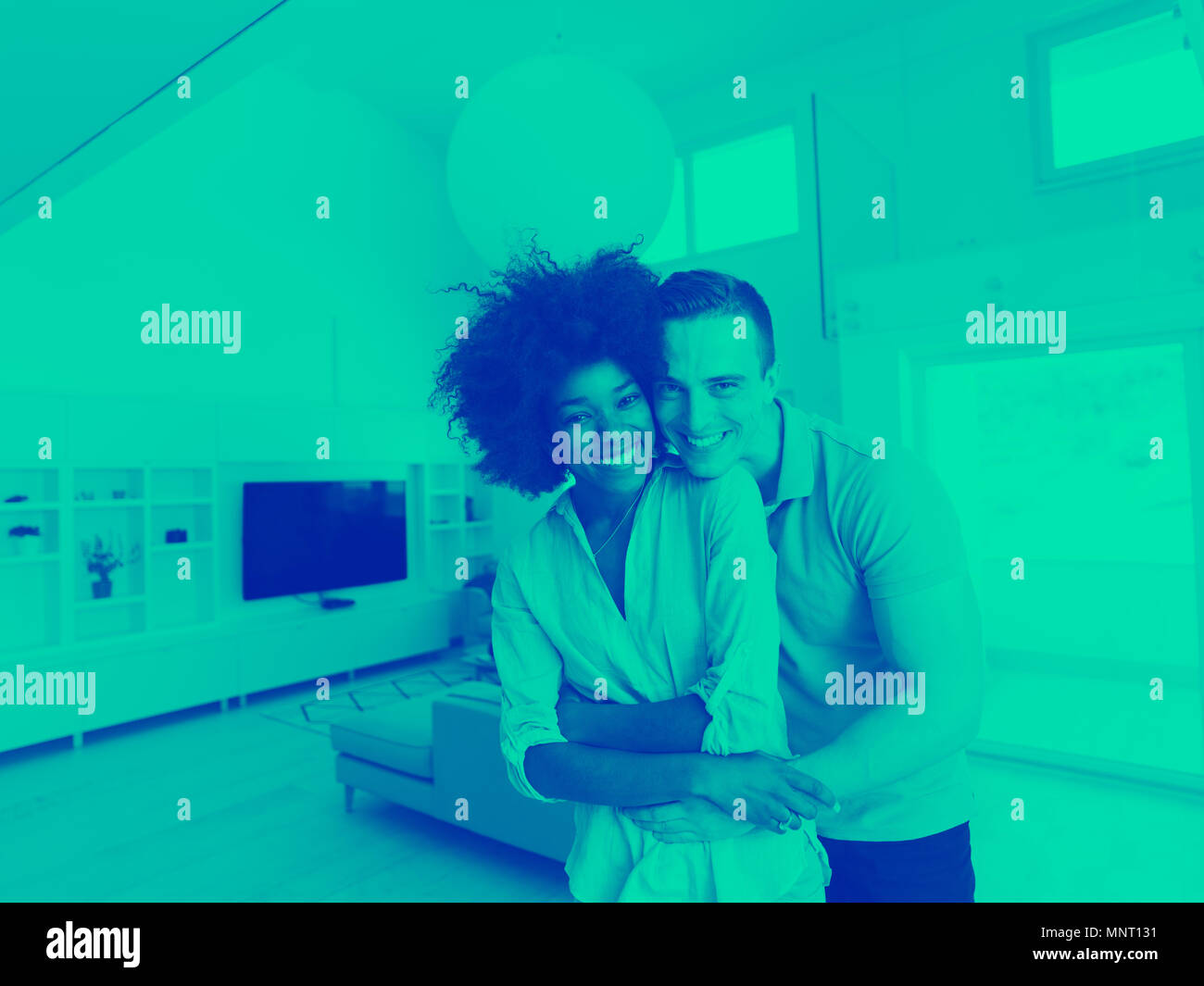 Giovane e bella coppia multietnica abbracciando nel loro nuovo appartamento Foto Stock