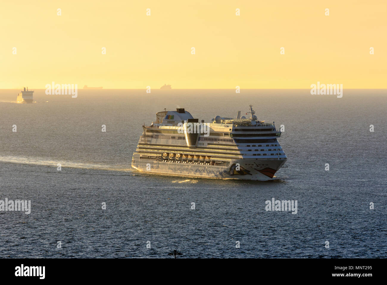 Inghilterra, Dover Harbour. AIDAluna all'alba sunrise haze a vela attraverso il canale verso Dover. Altre navi in foto. Foto Stock