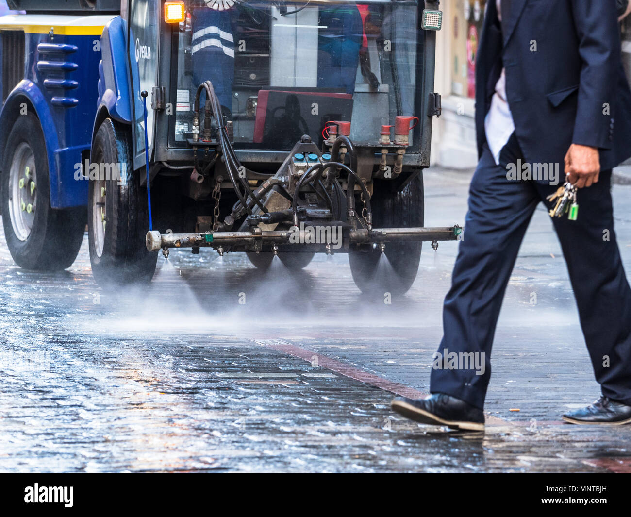 London Street pulizia - un uomo trattini di fronte a una strada di macchina di pulizia in Soho Londra centrale Foto Stock