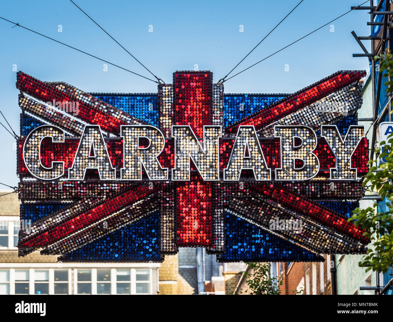 Giant sequinned Unione Jack segno pende su Londra famosa Carnaby Street fashion street nel West End di Londra Foto Stock