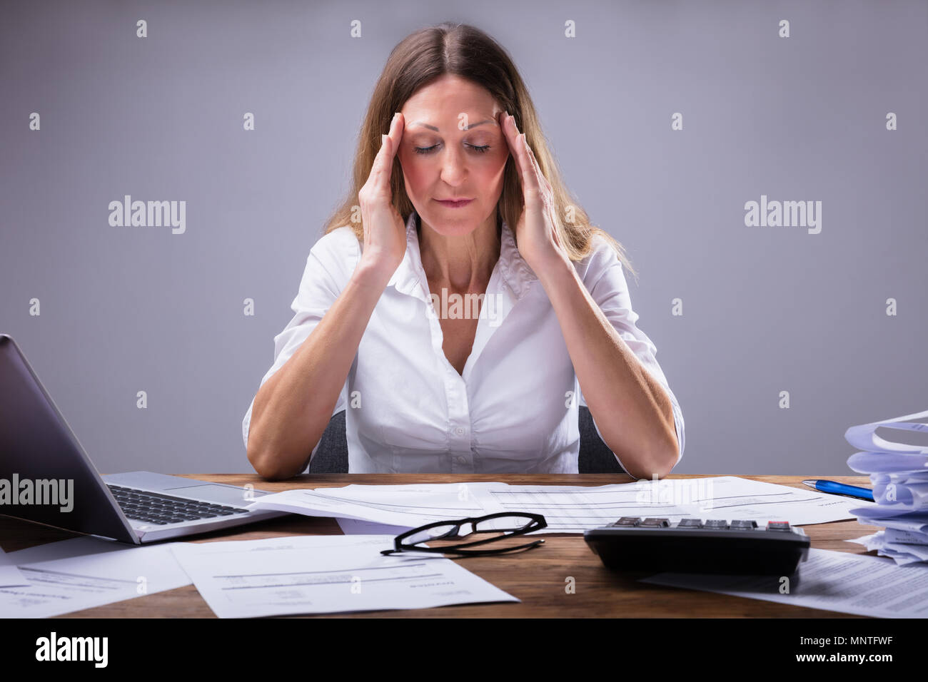 Imprenditrice che soffrono di mal di testa seduto in ufficio Foto Stock