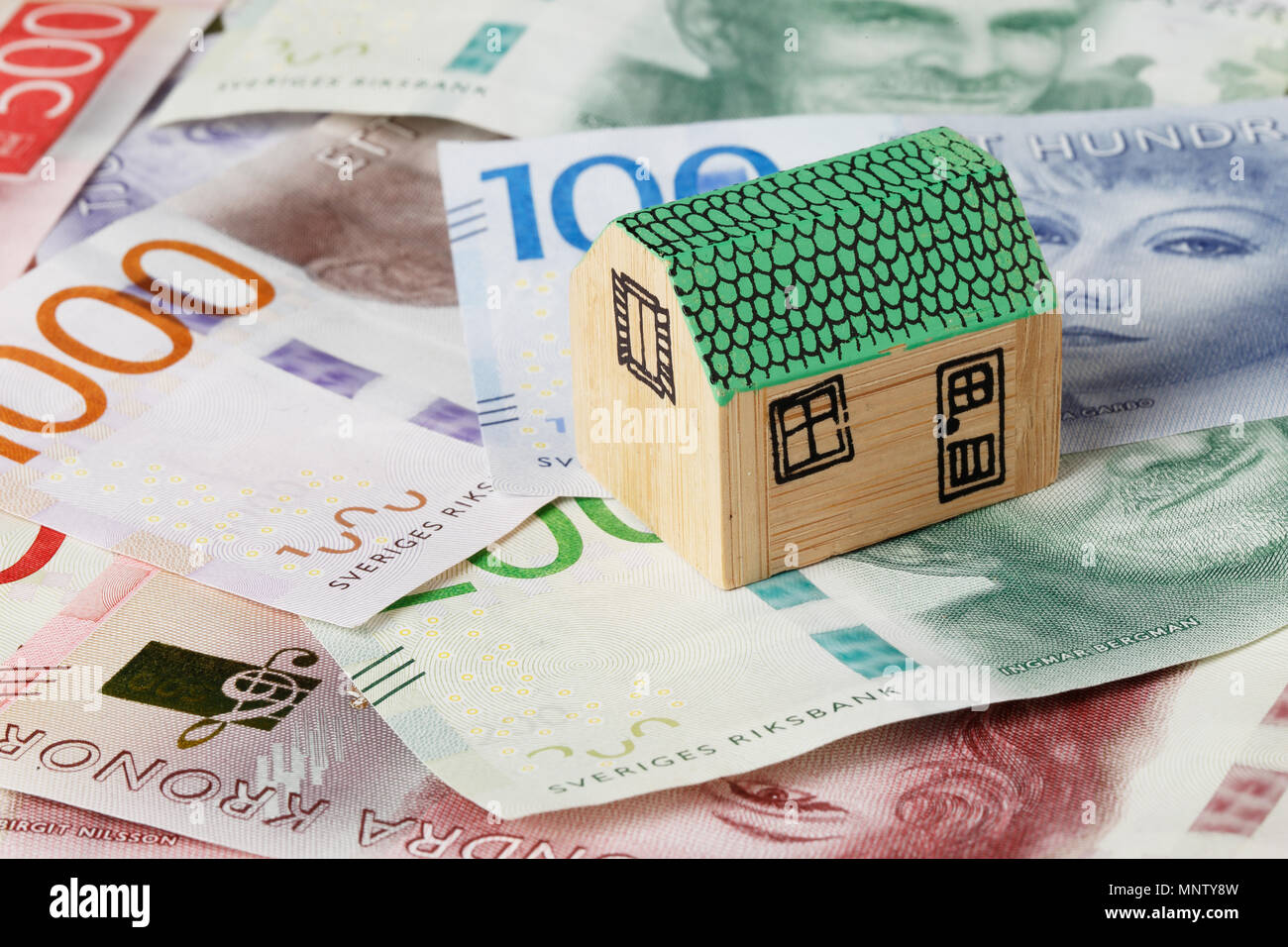 Stoccolma, Svezia - 10 Febbraio 2017: Piccola casa in legno con il tetto verde sulla parte superiore af banconote in svedese. Foto Stock