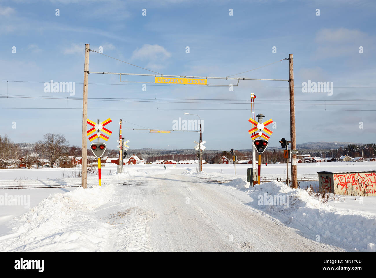 Gagnef, Svezia - 9 Febbraio 2018: svedese attraversamento ferroviario con barre, suono e segnali luminosi in campagna durante il periodo invernale. Foto Stock