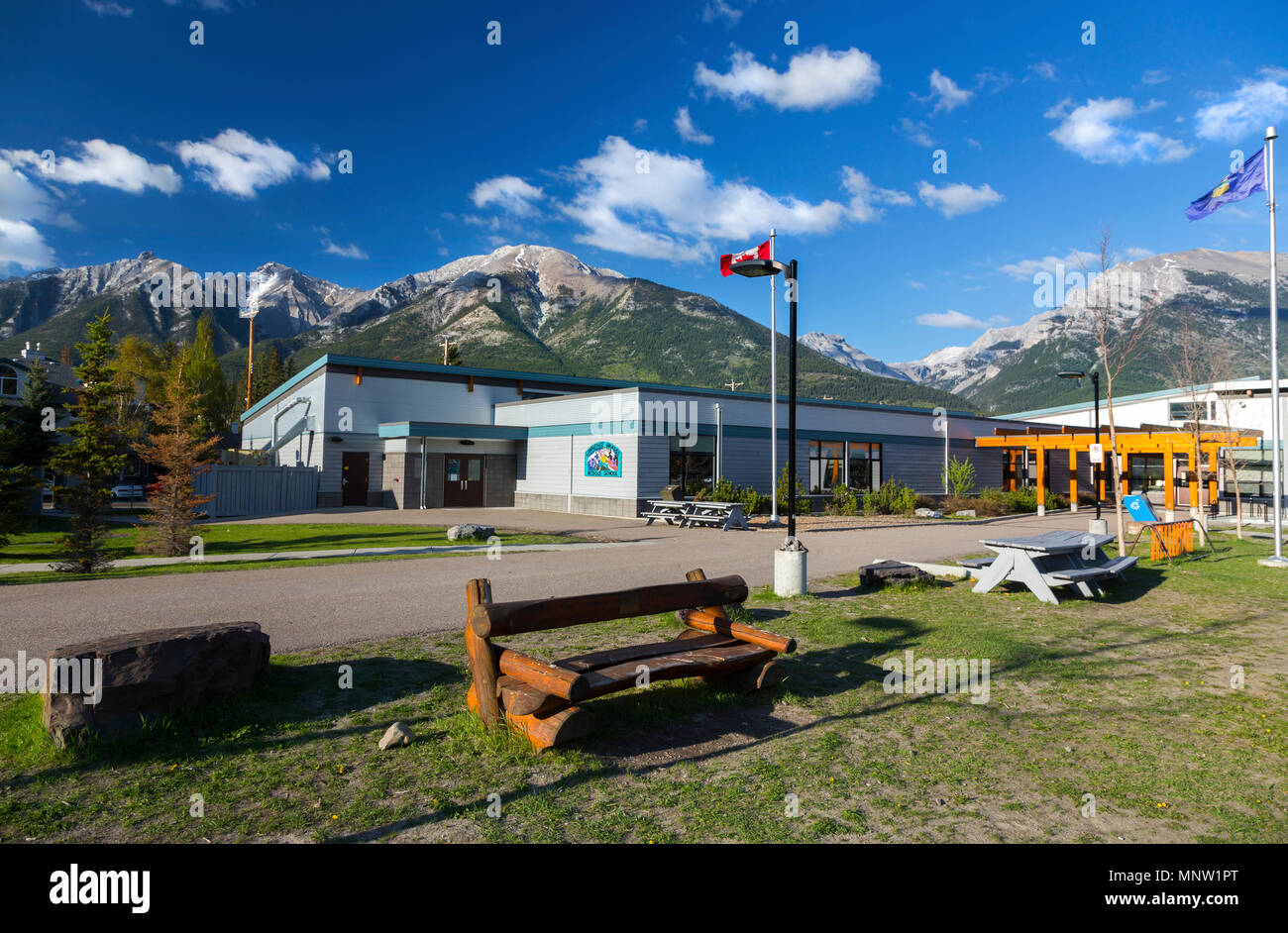 Lawrence Grassi Middle School esterno dell'edificio con la bandiera canadese e lontane montagne rocciose nella città di Canmore, Alberta Foto Stock