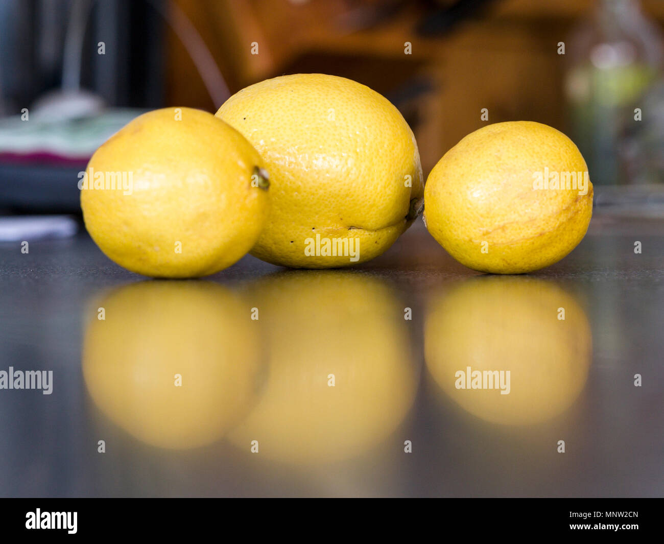 Tre limoni giallo: Tre limoni imperfetta riflessa su di un banco di cucina. Foto Stock