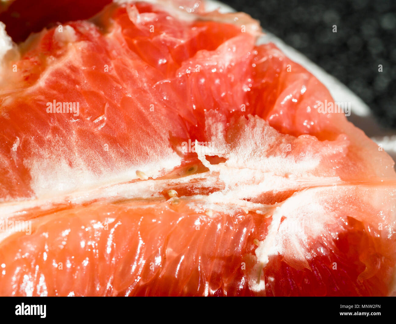 Vista dettagliata del rosso rubino Segmenti di pompelmi e di pomeli: un profondo pompelmo rosso aperto e pronto a mangiare brilla al mattino presto sun. Foto Stock