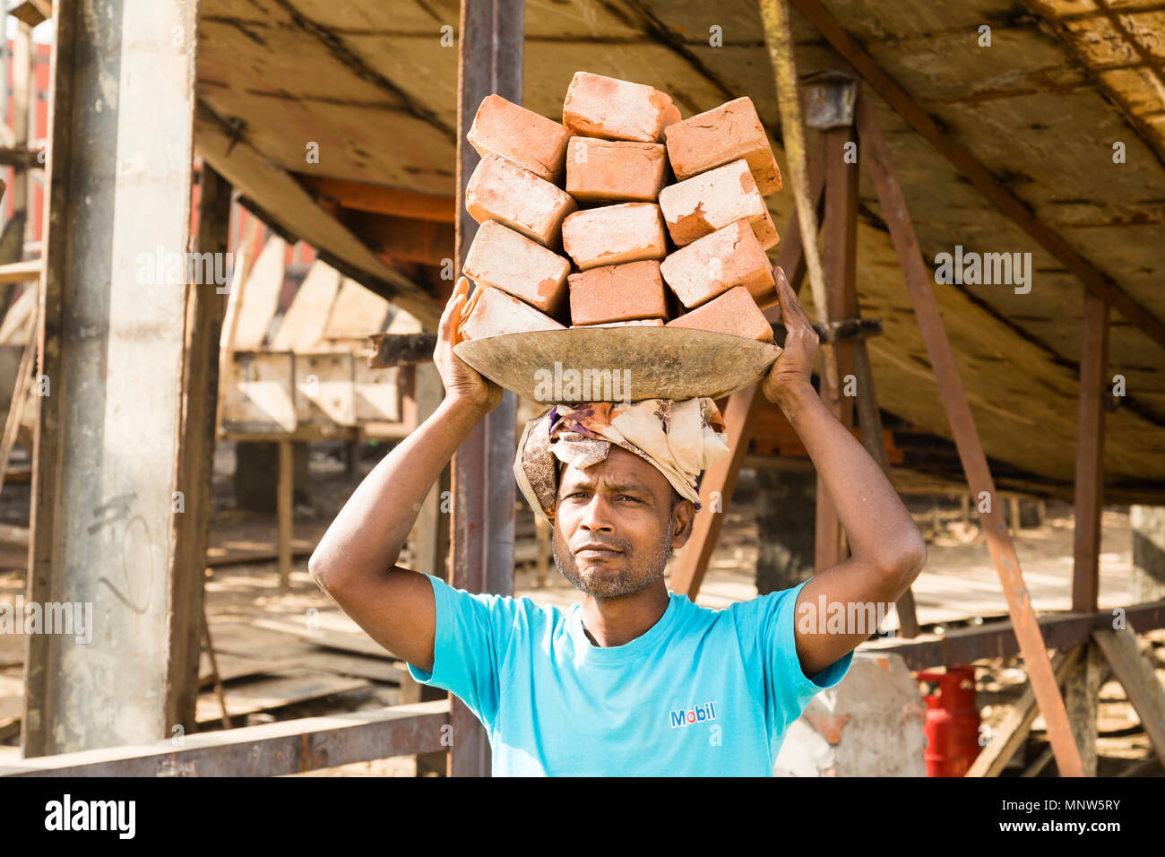 Dacca in Bangladesh, 24 Febbraio 2017: Nave dock a Dacca in Bangladesh, dove una nuova nave è prevista sulla chiglia. Di seguito è riportato un operaio che trasporta mattoni sulla sua testa Foto Stock