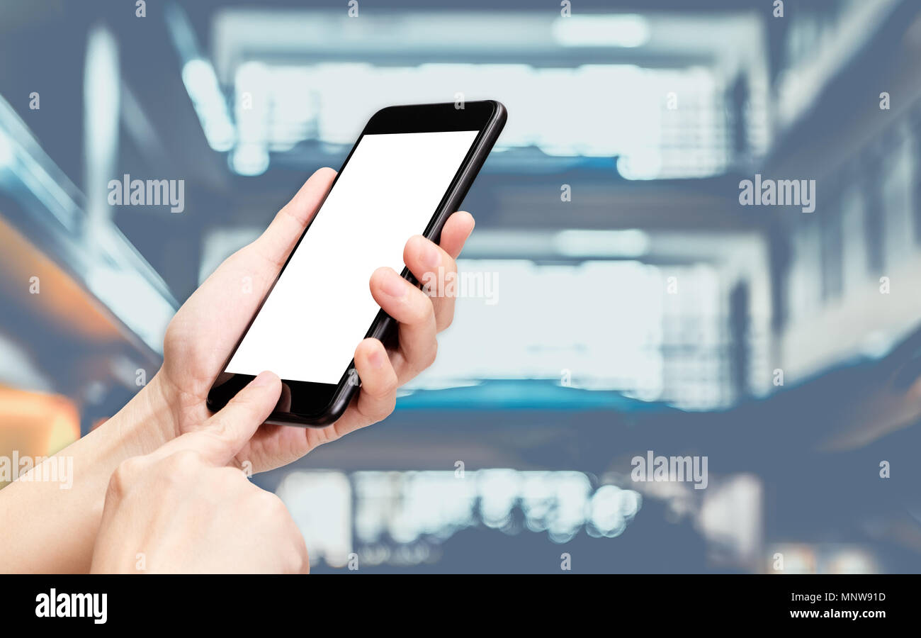 Mano fare clic su telefono cellulare con blur banca contatore al corridoio modo hall sfondo bokeh,luce schermata bianca mock up modello per aggiunta di un vostro disegno o si Foto Stock