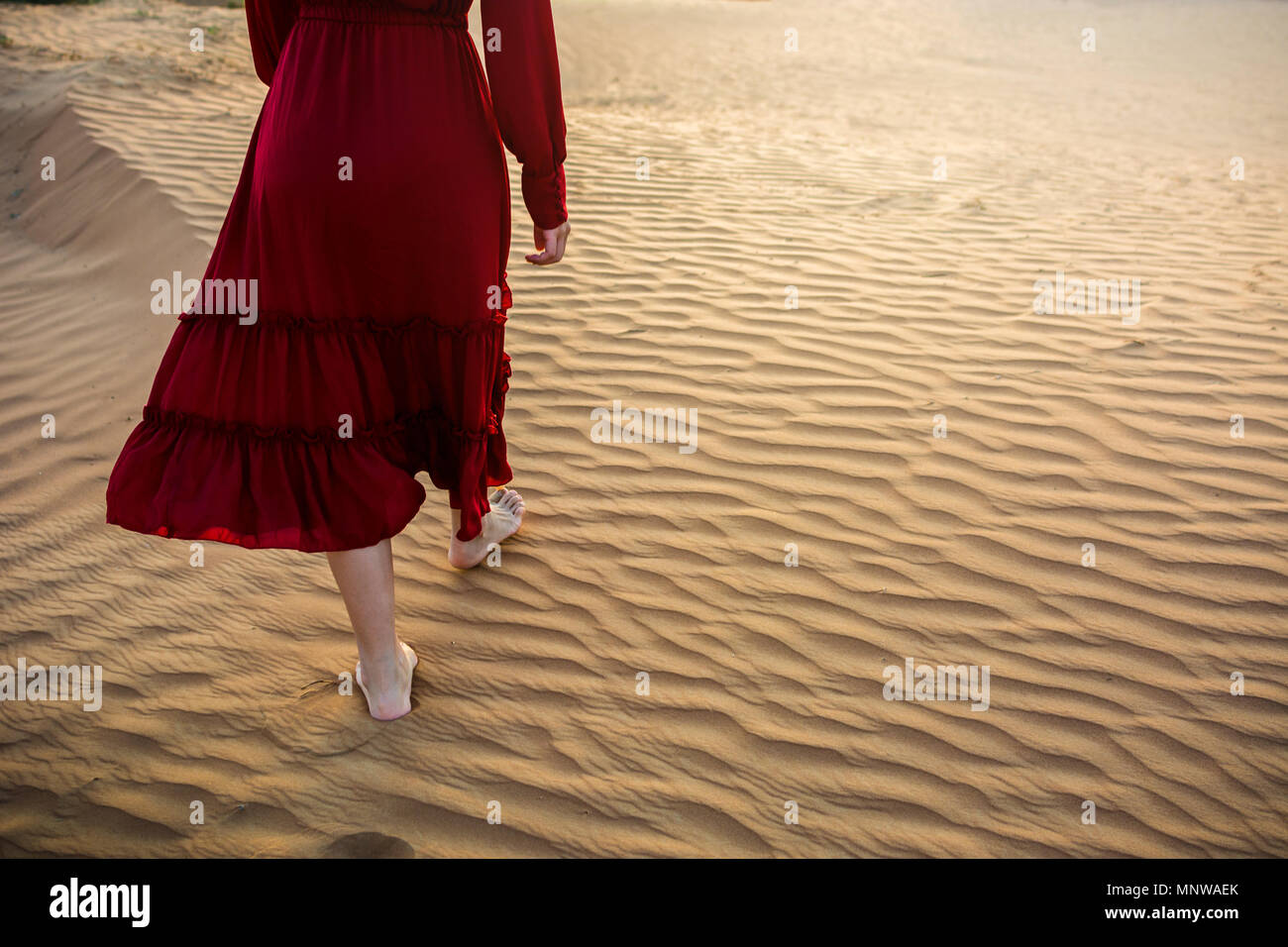 La donna a piedi nel deserto al tramonto vista posteriore Foto Stock