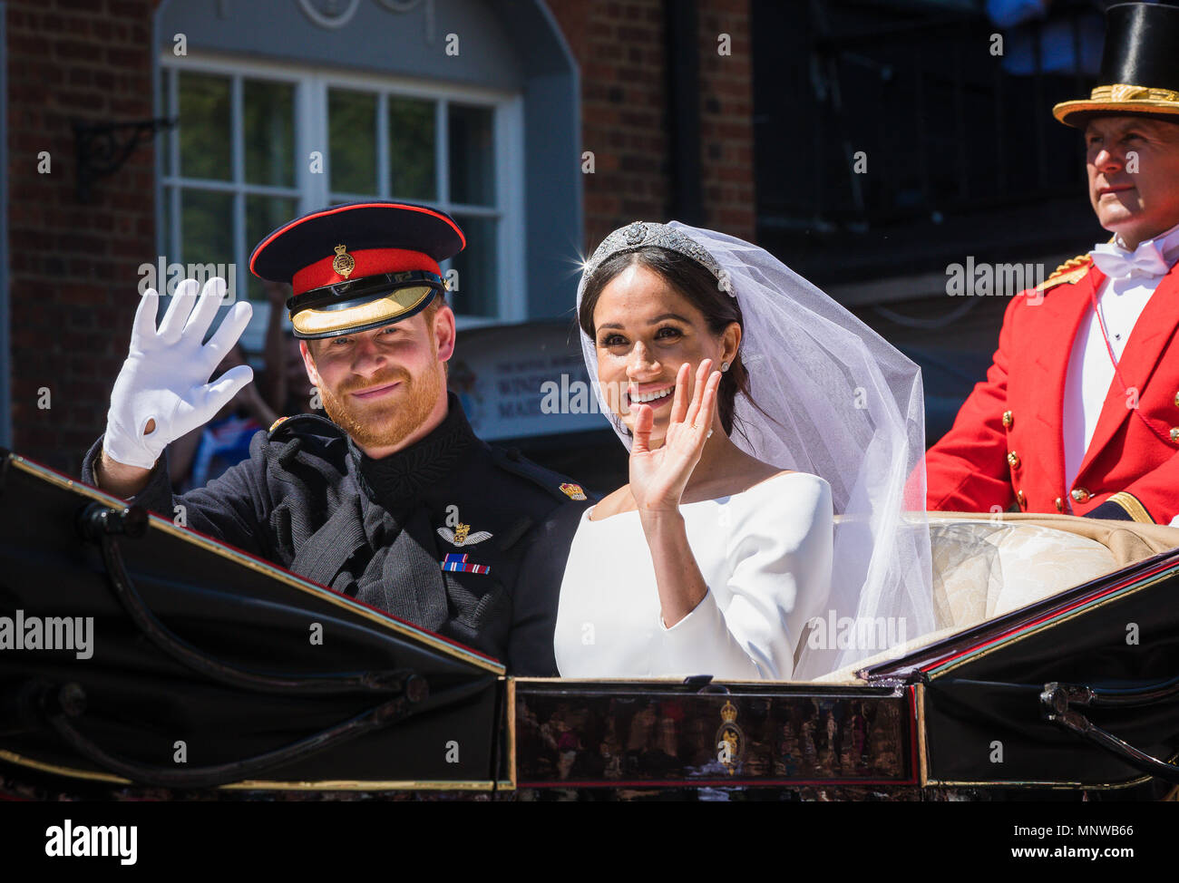 Windsor, Regno Unito, 19 maggio 2018. Il principe Harry e la sua sposa Meghan Markle ride in giro per le strade di Windsor in uno stato di Landau accolto da una folla numerosa tifo e sventolando bandiere a seguito del loro matrimonio in cappella di St Georges. Prima di rientrare al Castello di Windsor per il loro ricevimento di nozze. Essi saranno ora sapere come il Duca e la Duchessa di Sussex Foto Stock