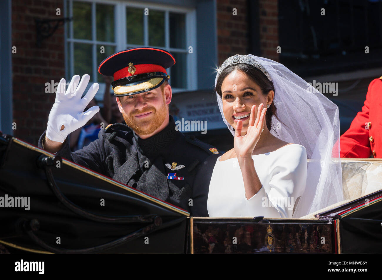 Windsor, Regno Unito, 19 maggio 2018. Il principe Harry e la sua sposa Meghan Markle ride in giro per le strade di Windsor in uno stato di Landau accolto da una folla numerosa tifo e sventolando bandiere a seguito del loro matrimonio in cappella di St Georges. Prima di rientrare al Castello di Windsor per il loro ricevimento di nozze. Essi saranno ora sapere come il Duca e la Duchessa di Sussex Foto Stock