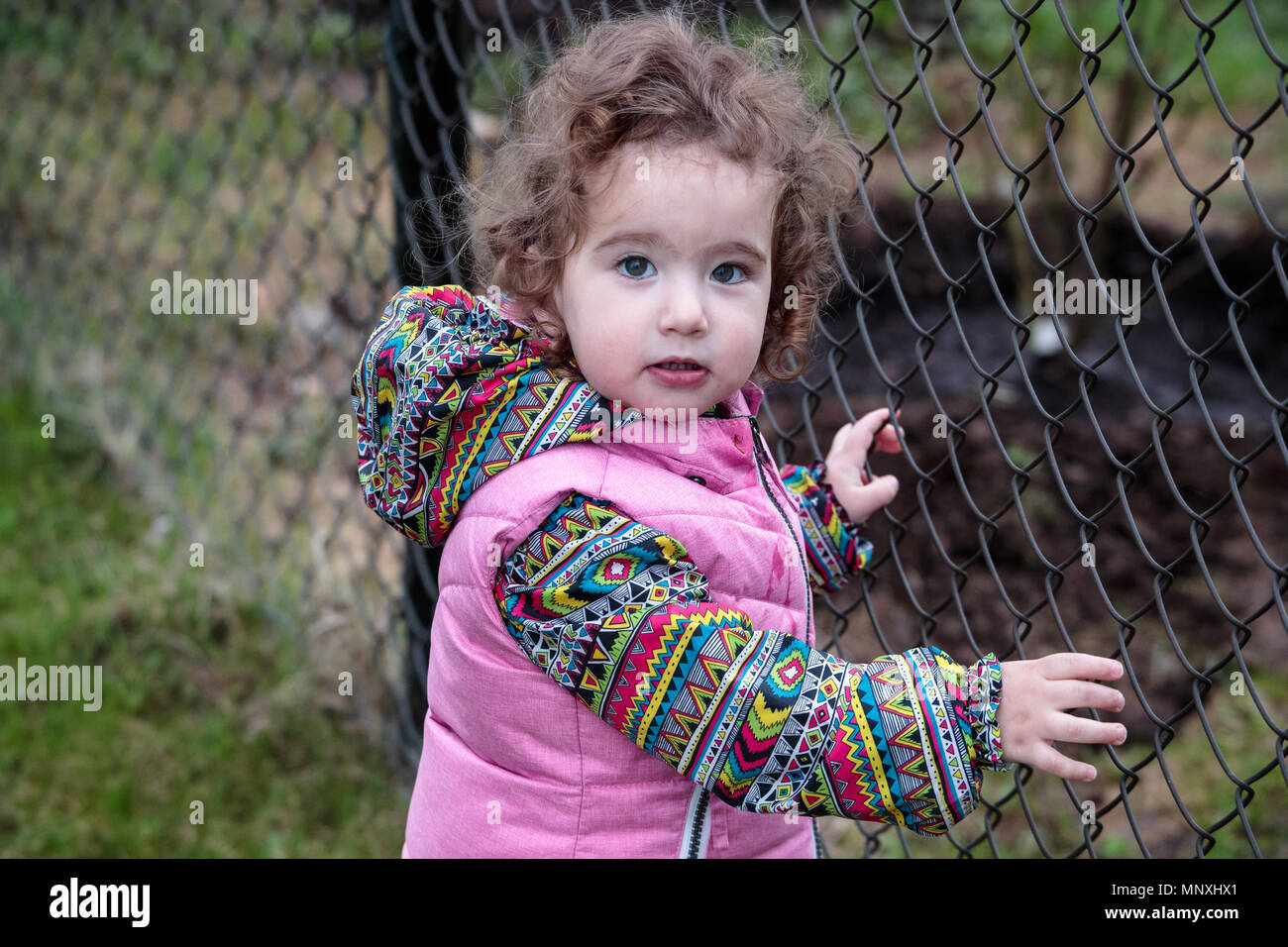 Piccolo bambino sulla strada vicino alla gabbia di maglia Foto Stock