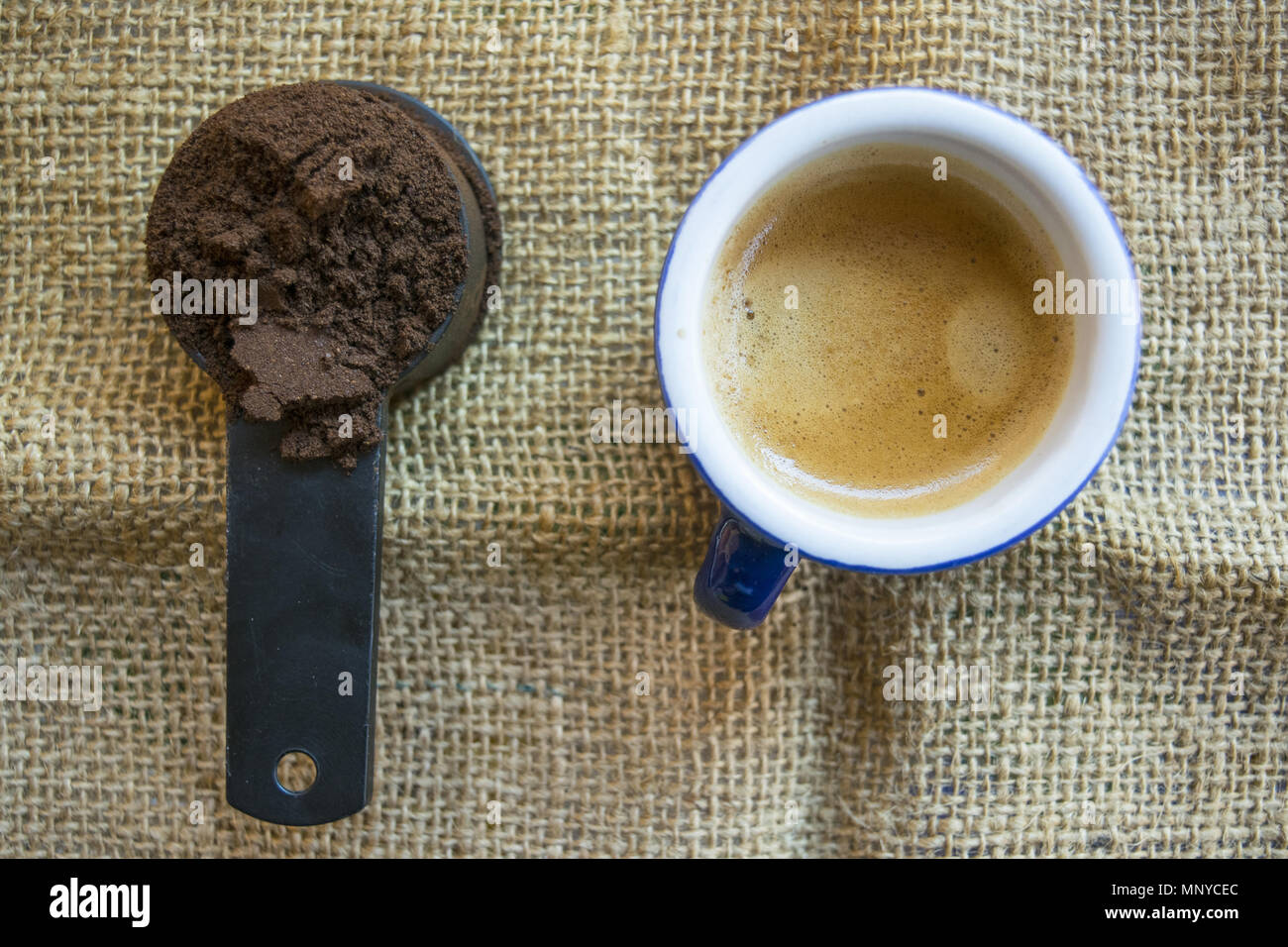 Misurino di macinato di caffè accanto una tazza di caffè espresso Foto Stock