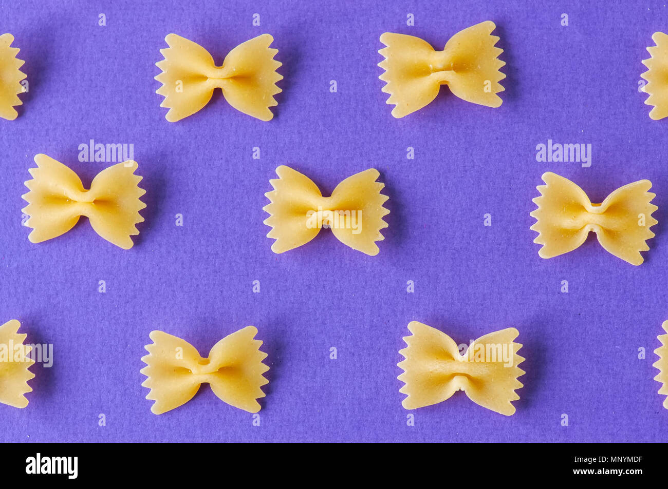 Diagonali di farfalle di pasta su uno sfondo violetto. Foto Stock