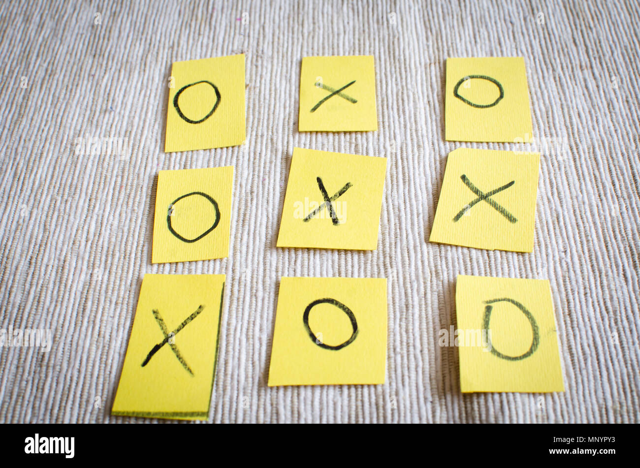 Tic Tac Toe Gioco , il vecchio classico gioco per due giocatori, lettere X e o su carta di colore giallo su sfondo a trama Foto Stock